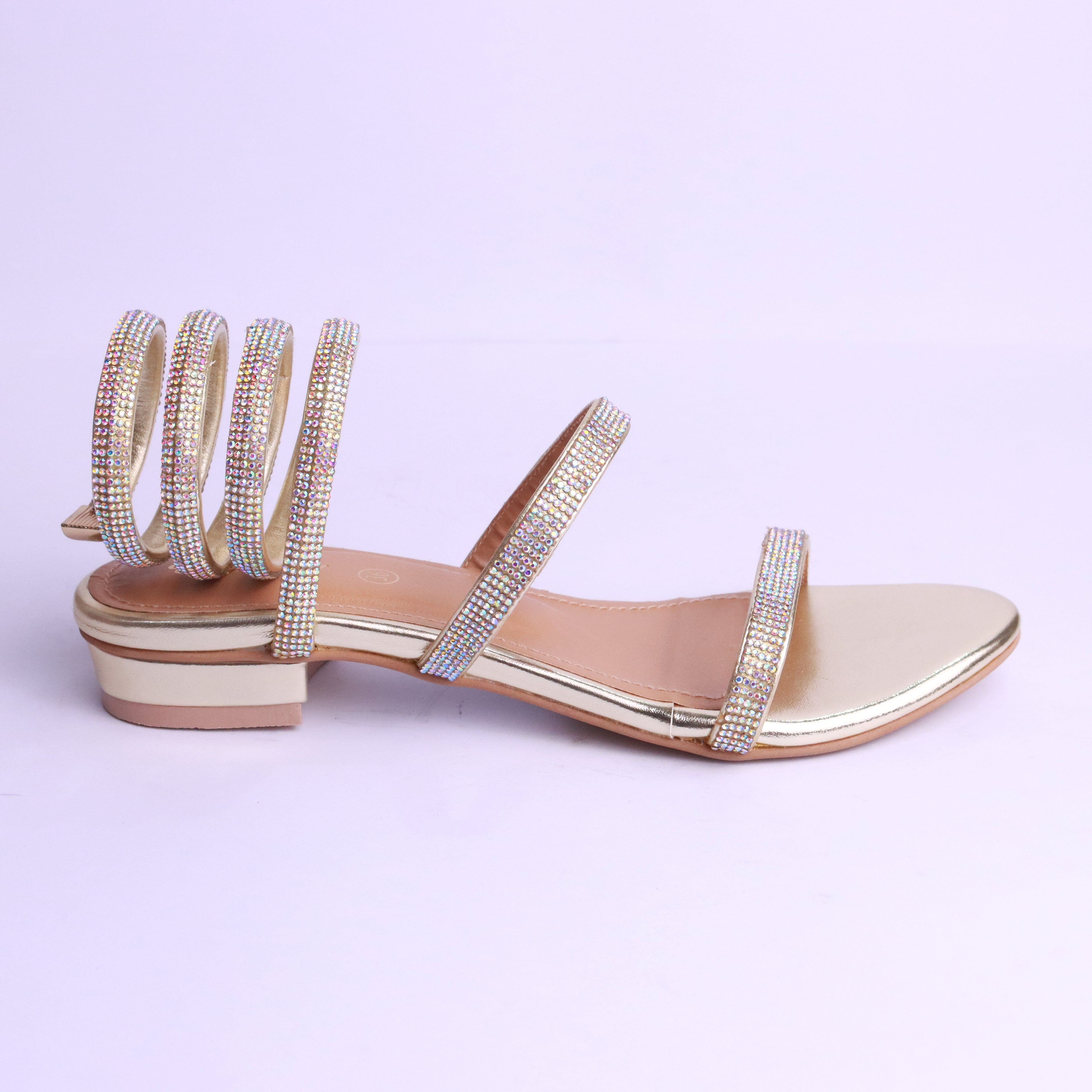 Red sandals with thin straps worn by a person on a wooden floor.