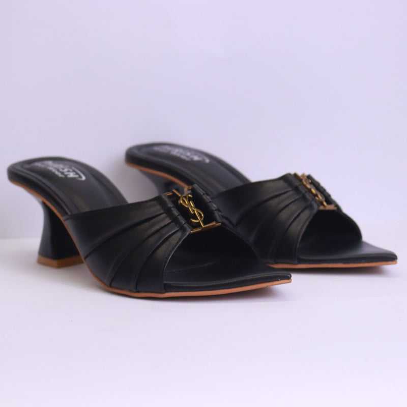 Black high-heeled sandals with a gold chain detail on a white background