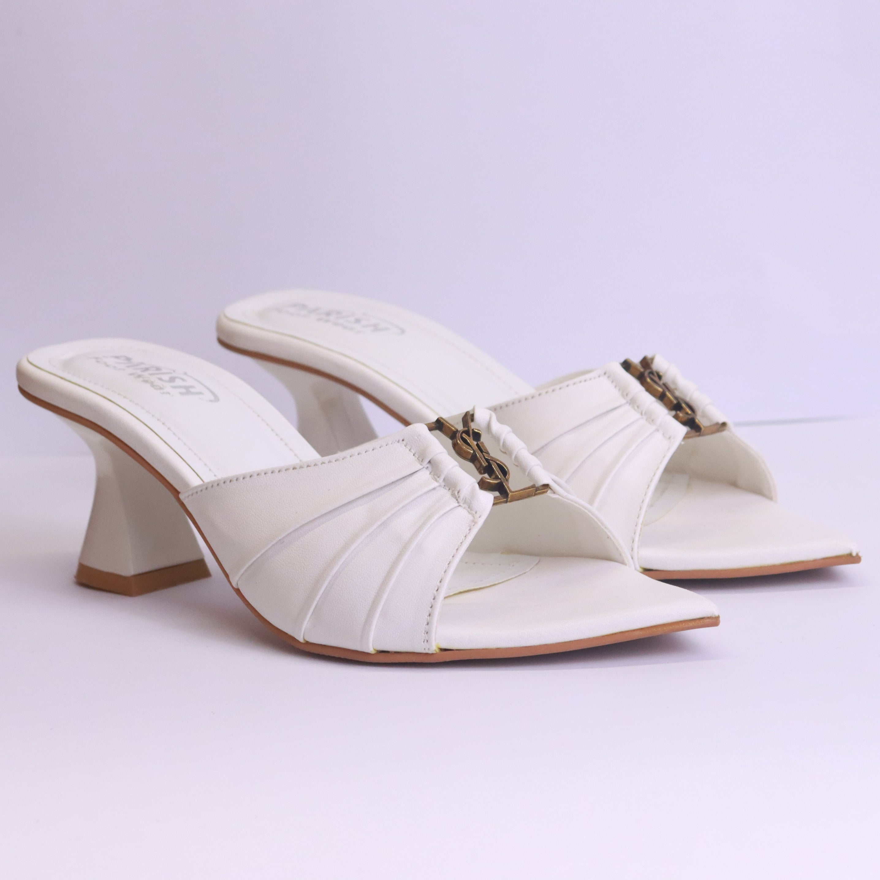 Pair of white high-heeled shoes with a decorative strap on a light purple background
