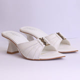 Pair of white high-heeled shoes with a decorative strap on a light purple background