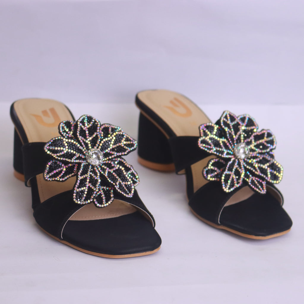 Black sandals with decorative flowers on a white background