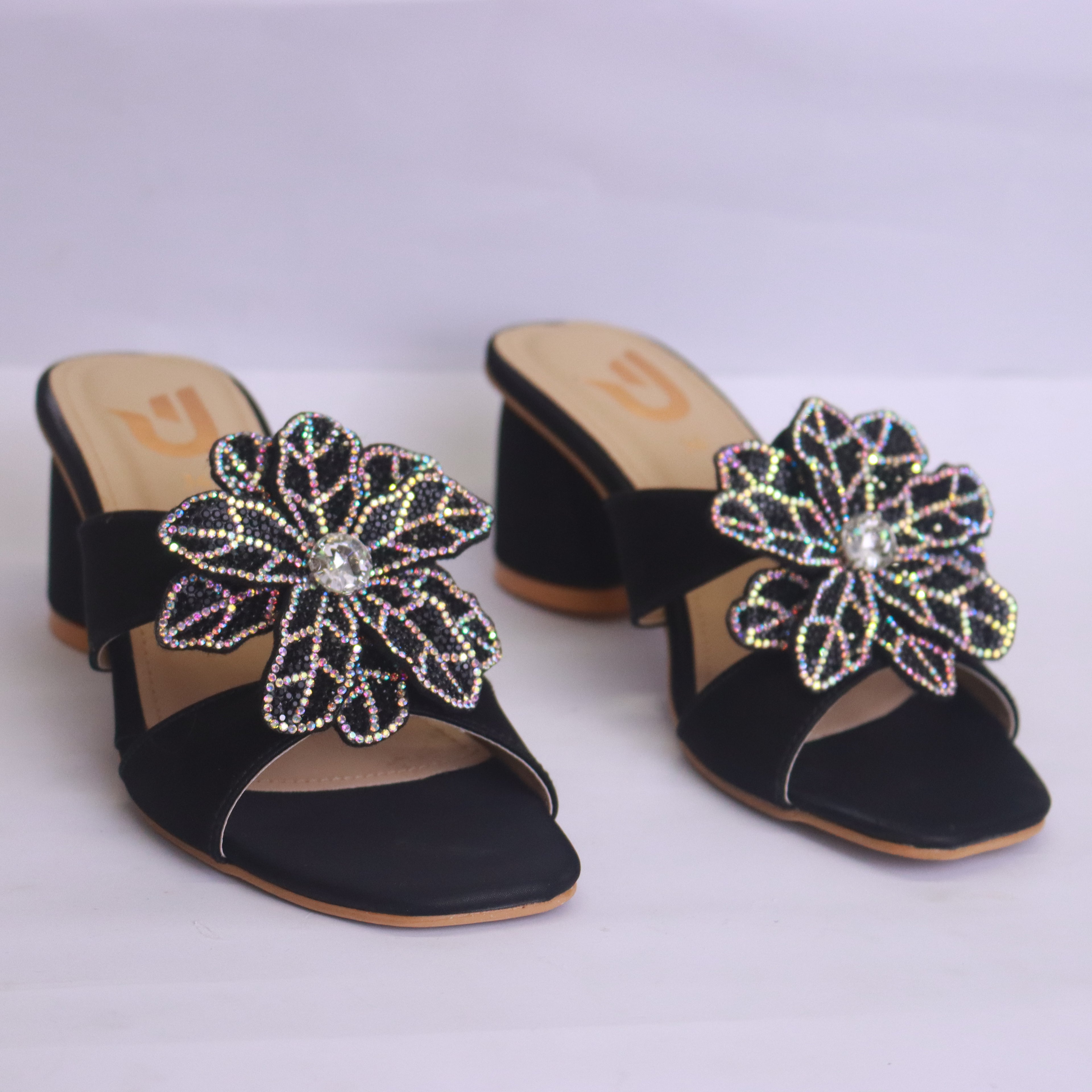 Black sandals with decorative flowers on a white background