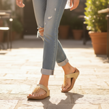 Person wearing light blue jeans and beige sandals on a patio