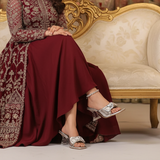Woman in a red and gold dress sitting on an ornate couch with decorative background